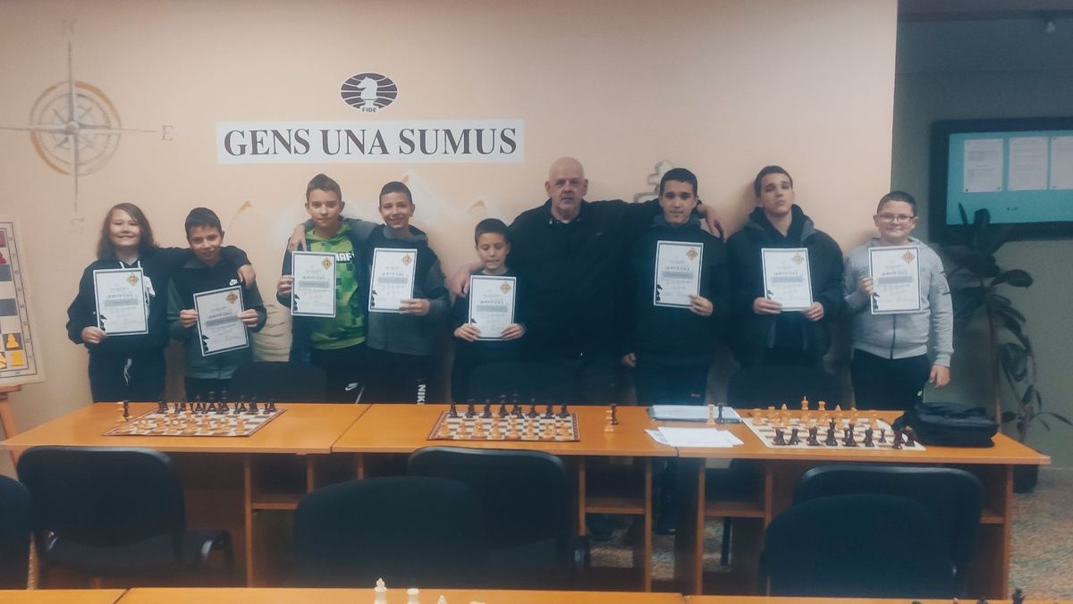 Grupa mladih šahista sa diplomama ispred table sa natpisom Gens una sumus